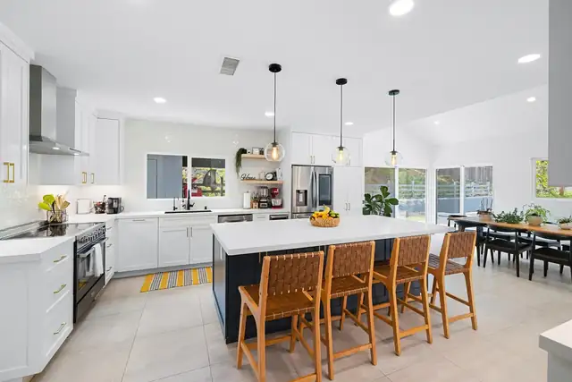 Del Mar kitchen remodel with bright white cabinets, navy island and woven leather stools