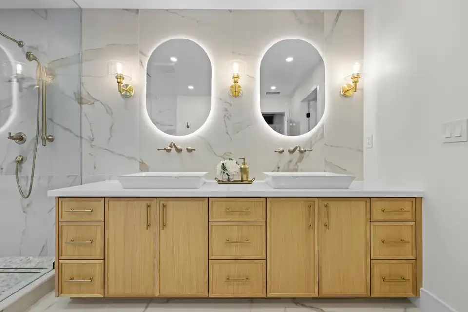 Bathroom remodeling San Diego: luxury bath with marble slab walls, floating oak vanity and backlit oval mirrors