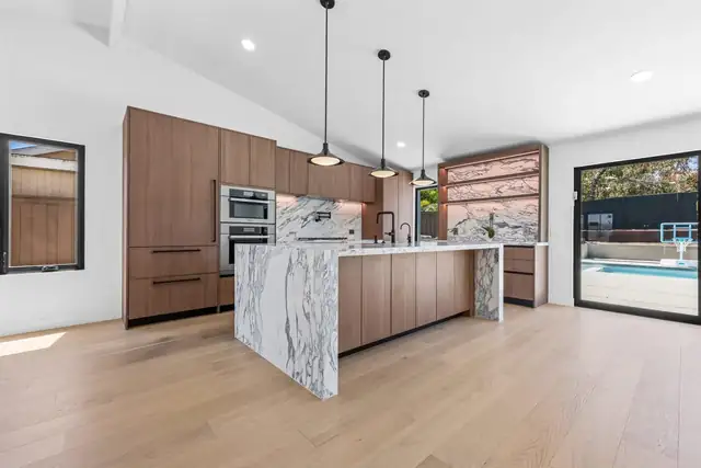 Encinitas kitchen remodel with walnut cabinets, marble waterfall island and pool-view sliders