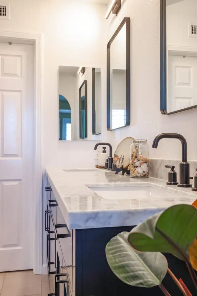 Sorrento Mesa bathroom remodel with navy vanity, marble counter, black framed mirrors and matte black fixtures