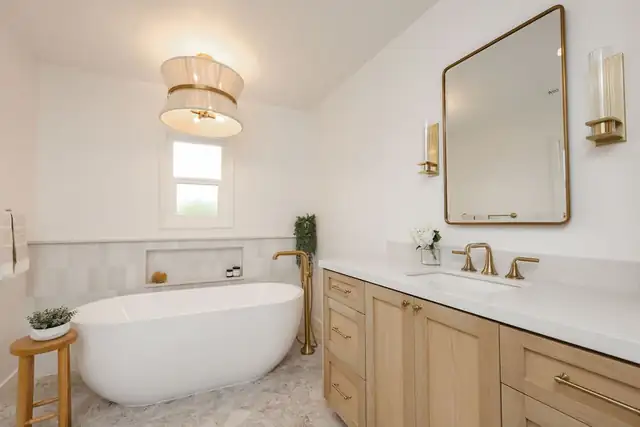 Primary bathroom by Craft Home Remodeling with a freestanding tub, brass floor-mounted filler and a white oak vanity