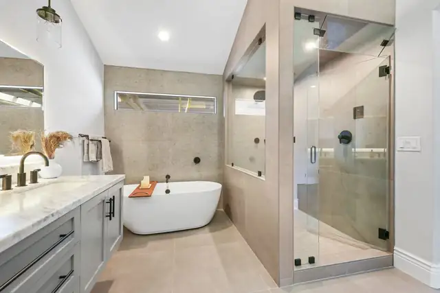 Primary bathroom with a freestanding tub, glass walk-in shower and a marble-topped gray vanity